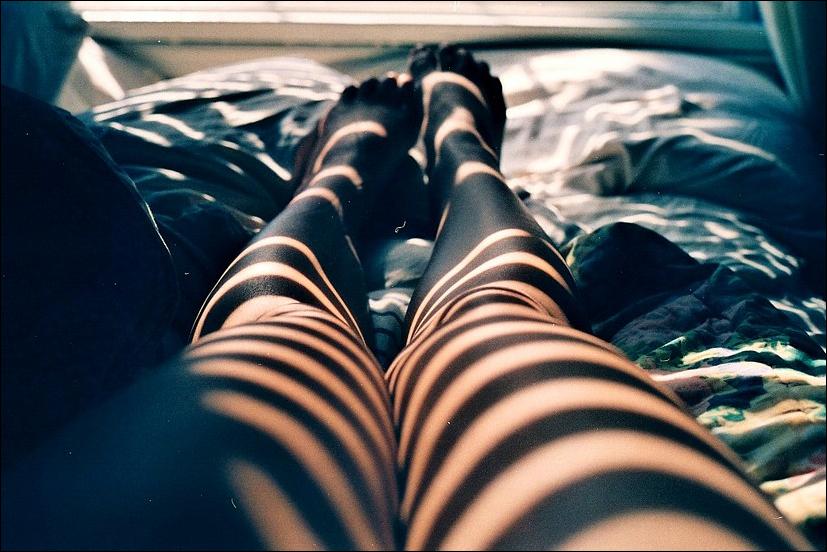 Лежа на черном диване нимфа задирает ноги показывая сочную писю